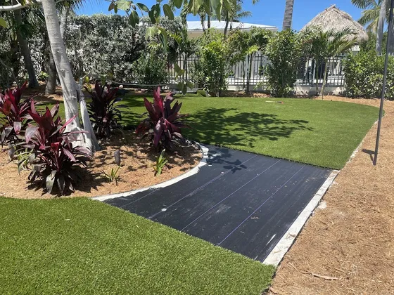 Poured white concrete border framing a weed-barrier panel between finished turf